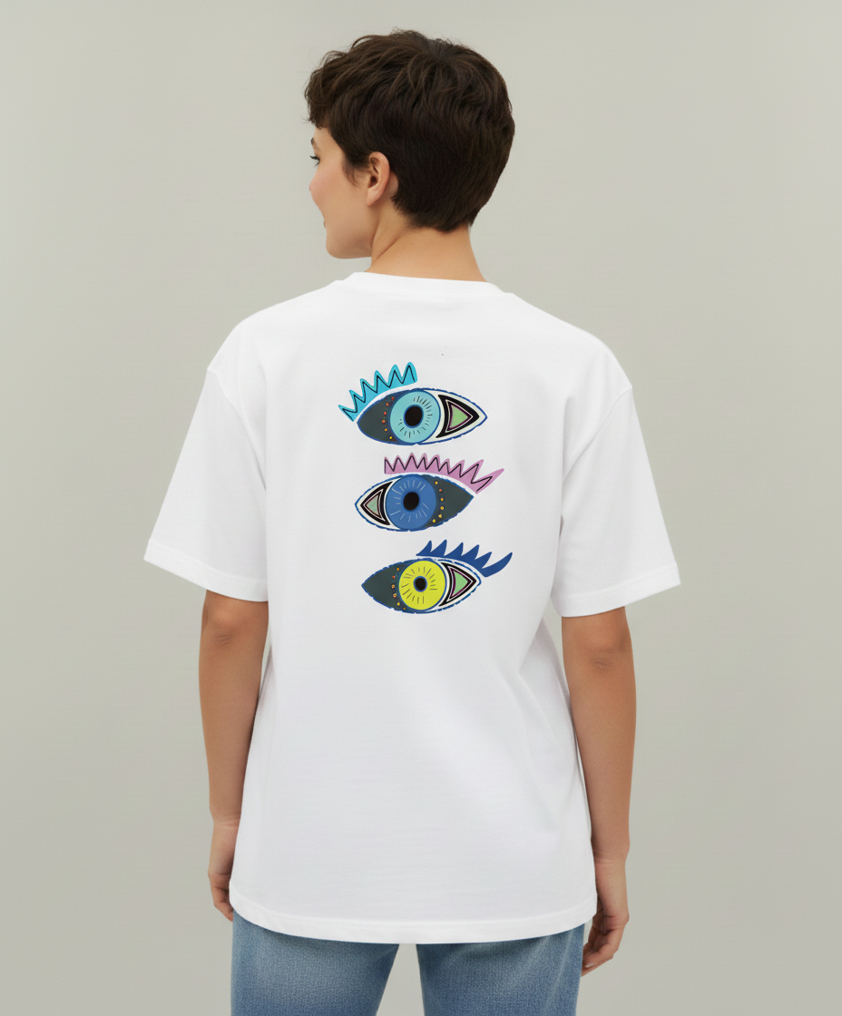 Woman wearing a white t-shirt from Semiotica with colorful eye designs on the back against a plain background
